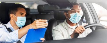 Fahrlehrer und Fahrschüler mit Medizinmaske im Auto